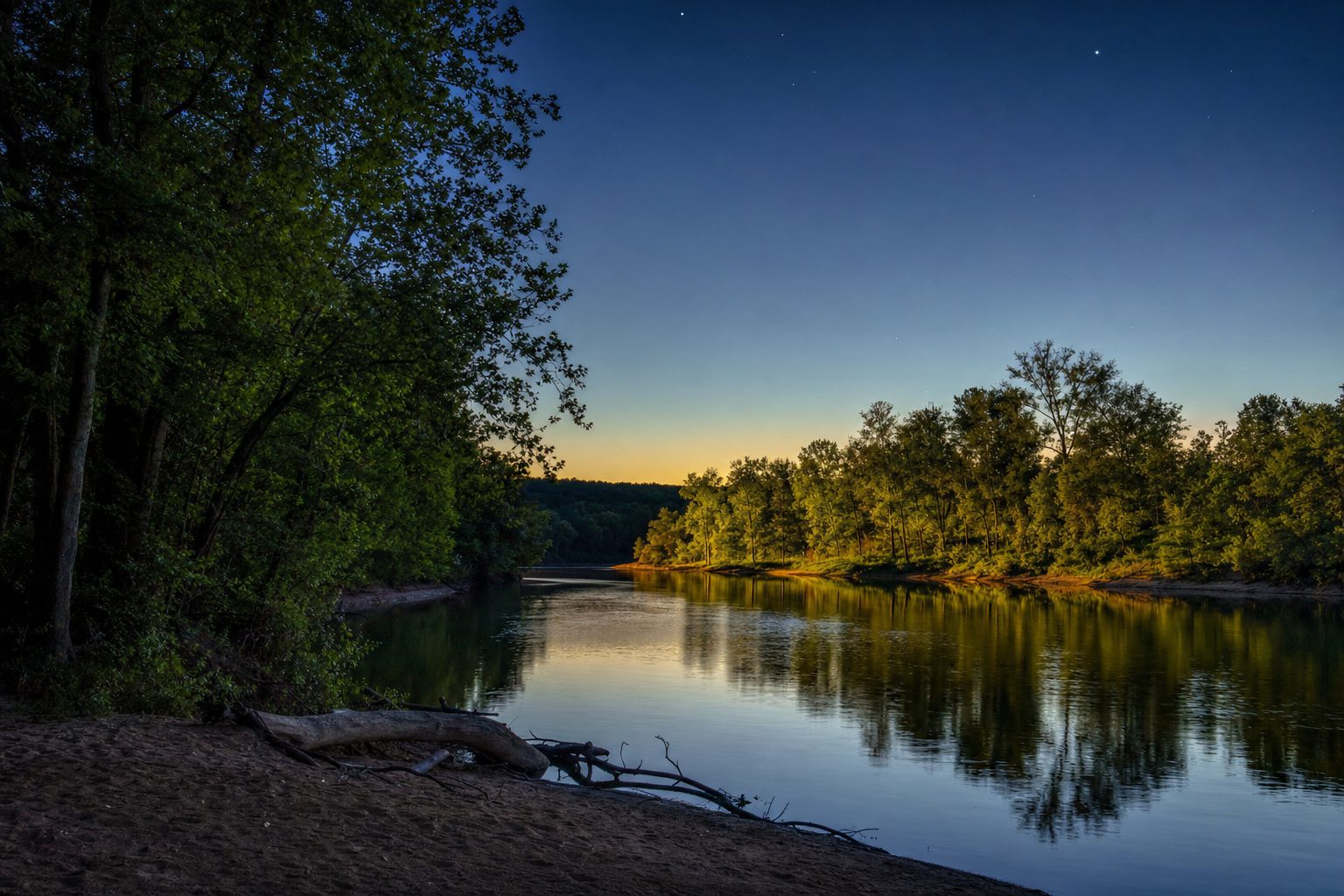 A calm river bend reflecting trees at dusk